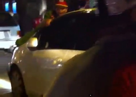 Cảnh sát bám trên nắp capô đi dọc tuyến phố Hà Nội. Ảnh cắt từ clip.